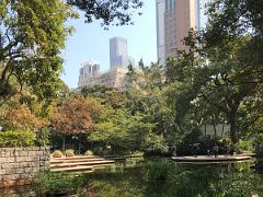 11A A small lake surrounded by trees in Kowloon Park with Lokville Commercial Building beyond Tsim Sha Tsui Kowloon Hong Kong